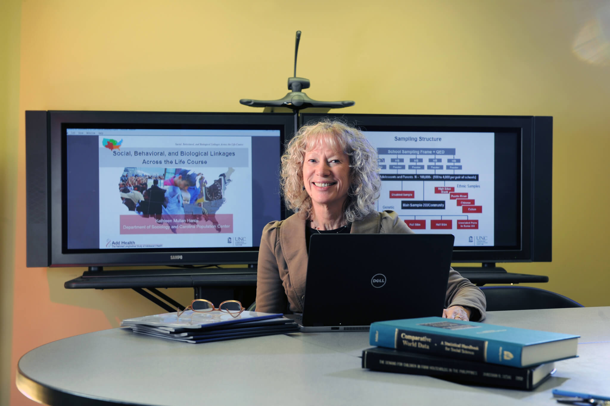 Kathleen Mullan Harris sits at a desk in front of two monitors