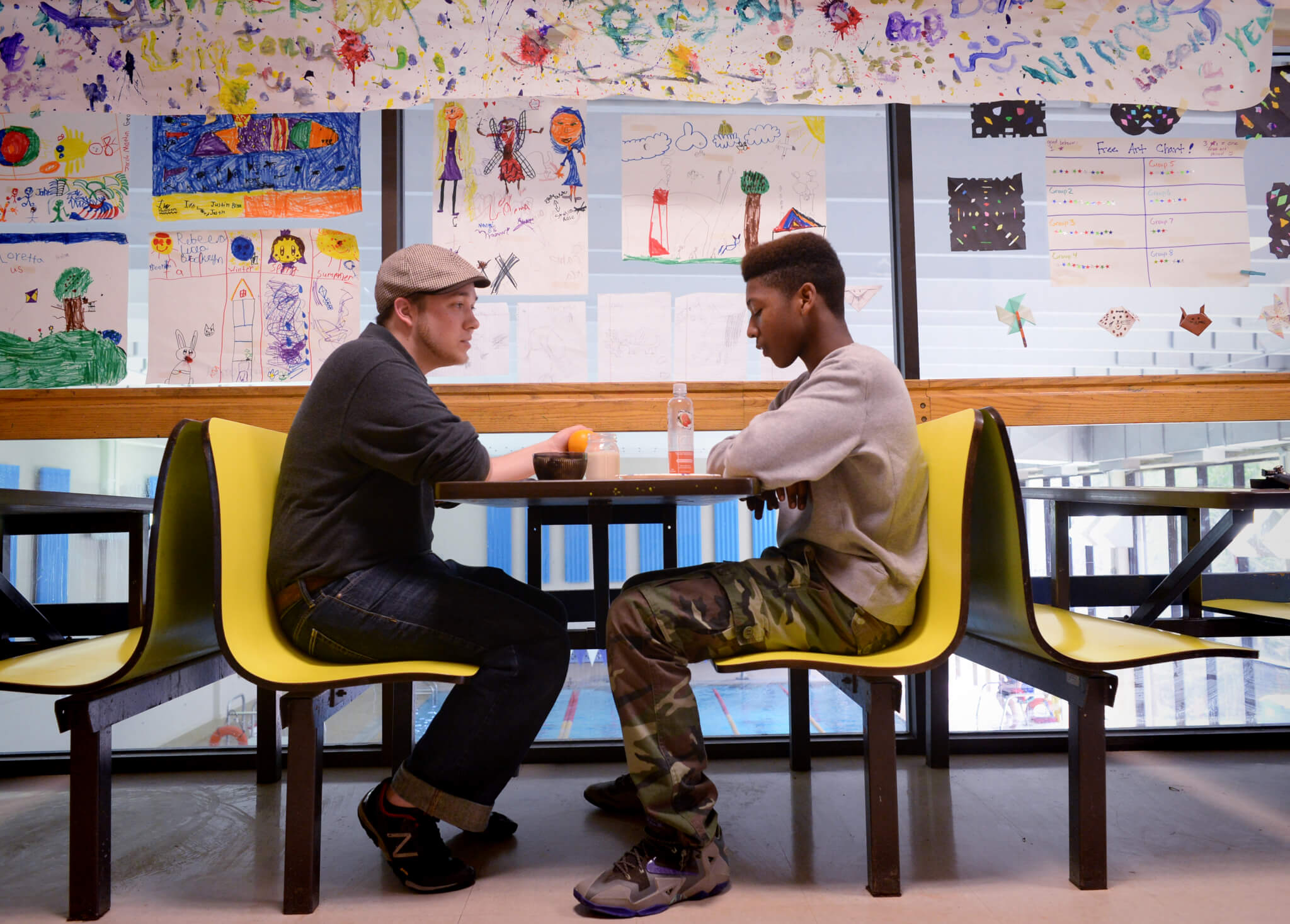 J.E. Misz sits at a yellow table and talks with Tahjay Wade.