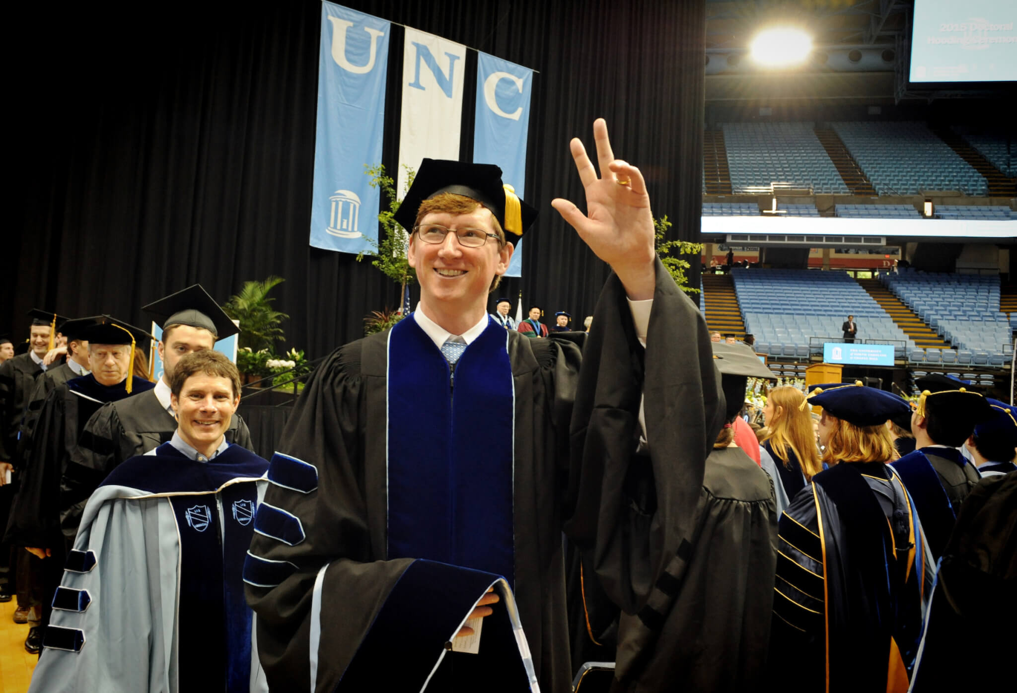 A graduate waves to family.