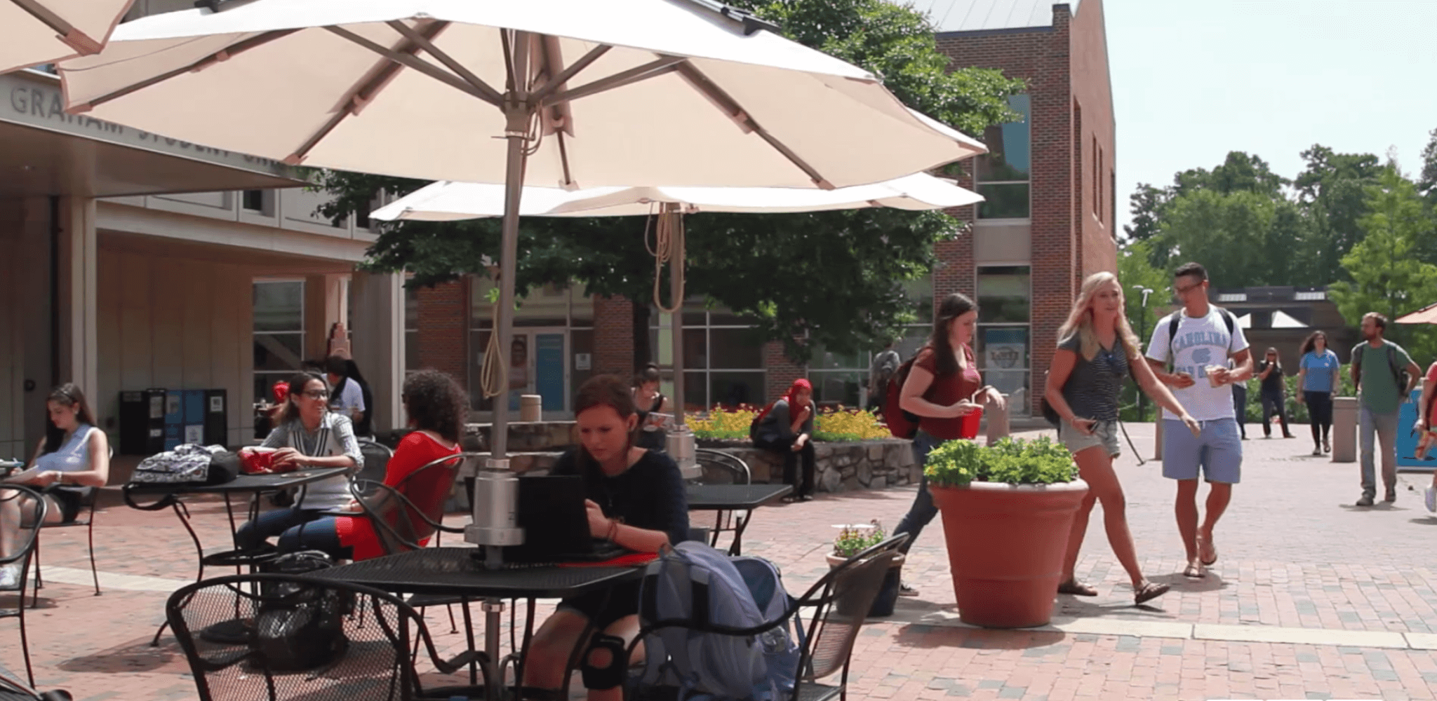 A student sits at a picnic table that has a solar umbrella