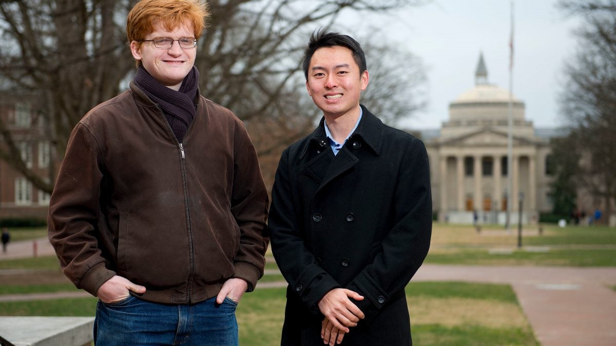 The two students stand together posing for photo.