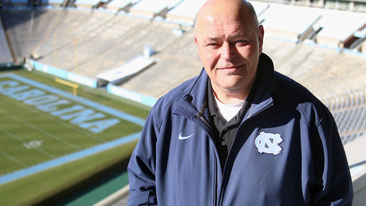 James Spurling stands on top steps of stadium with field in the background.