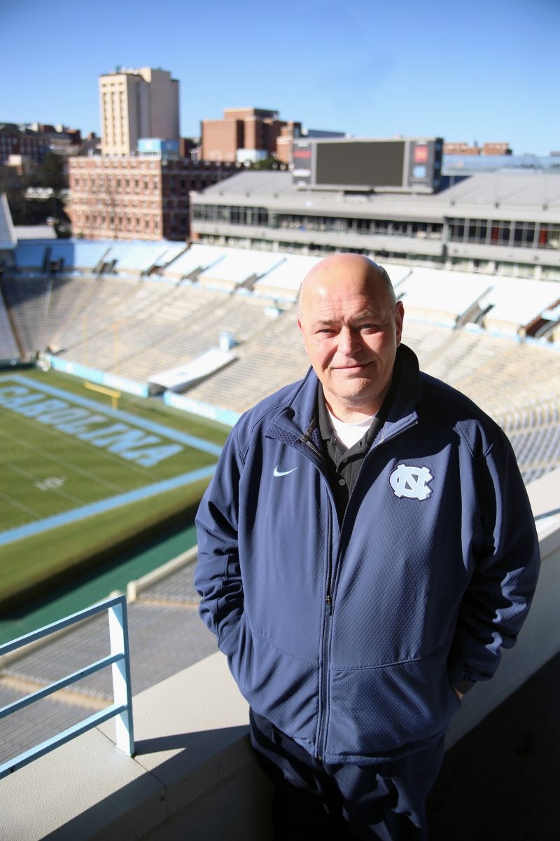 James Spurling stands on top steps of stadium with field in the background.