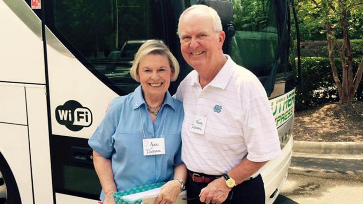 Woody Durham stands with woman in front of bus.
