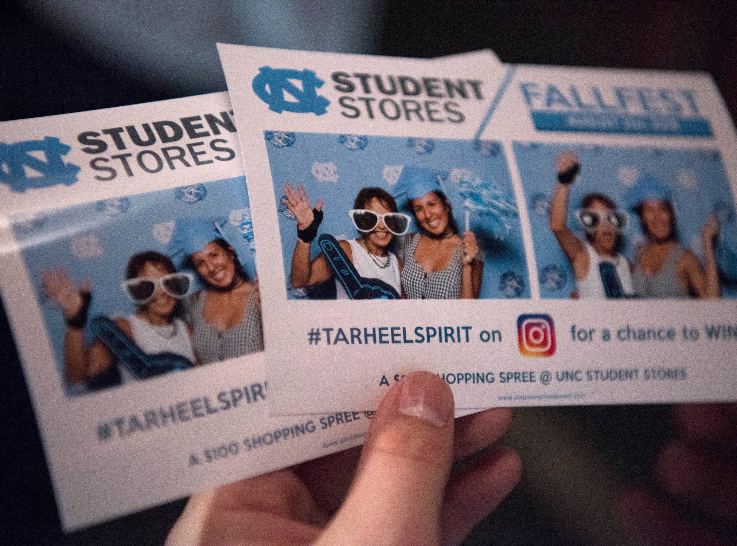 A hand holds flyers for fallfest.