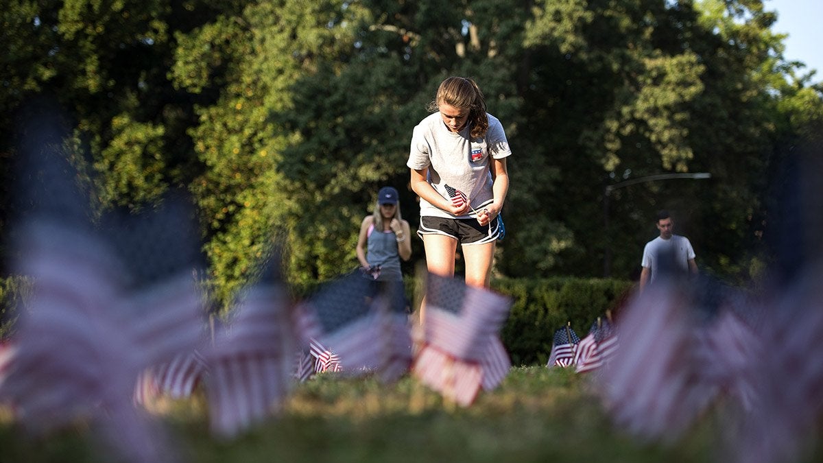 Student plants flag in the grass.