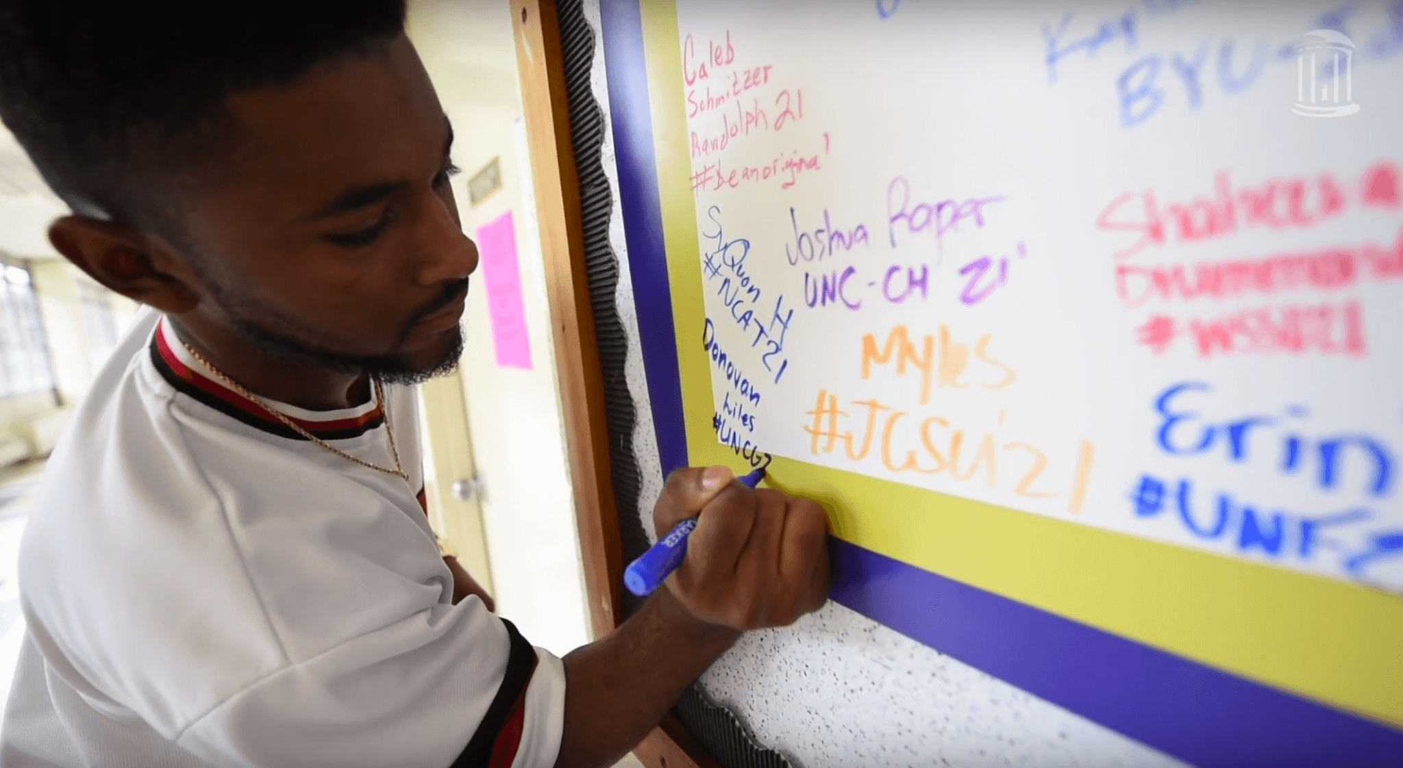 Student signs a poster board.