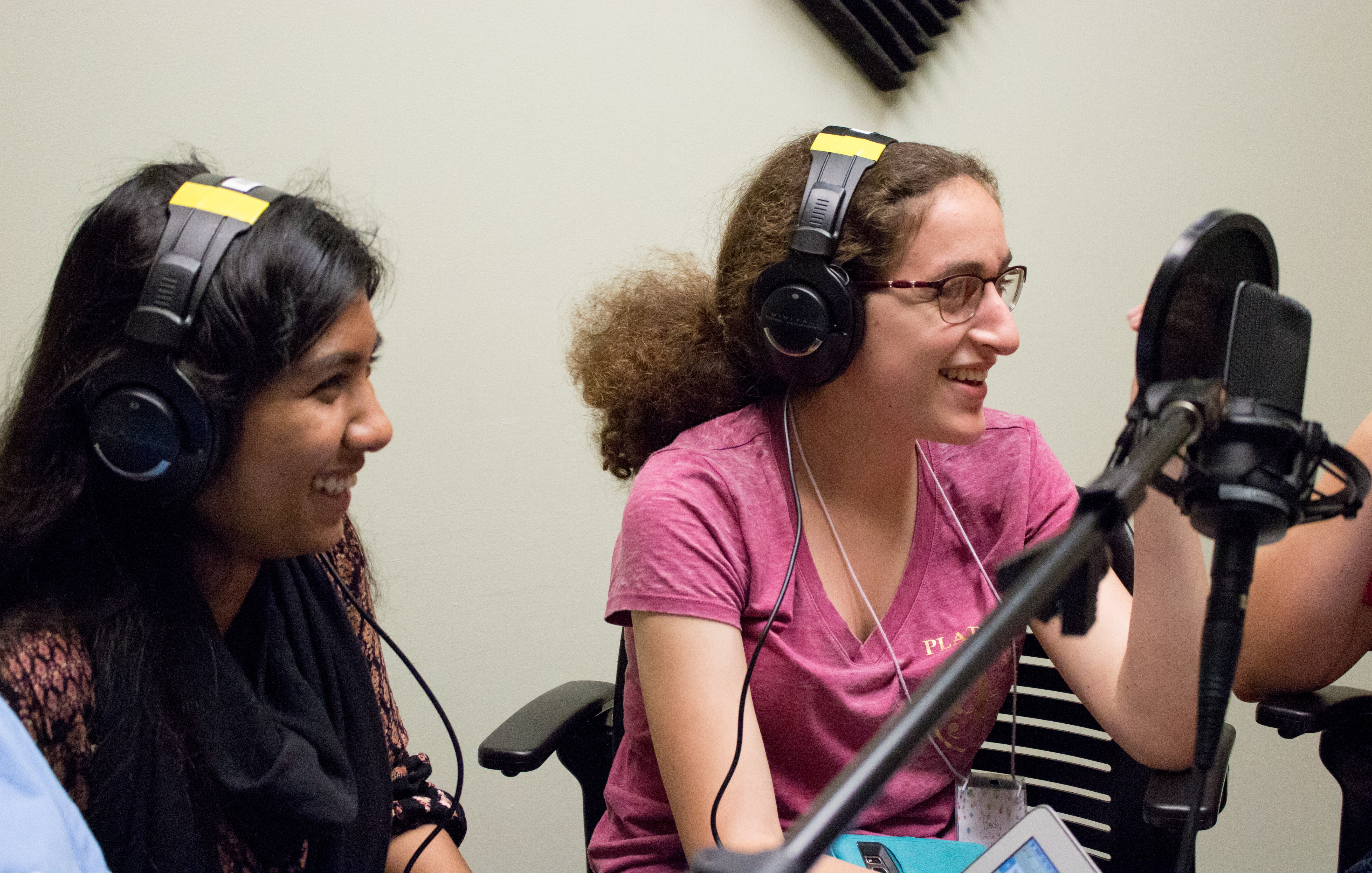Two young women in the Girls talk Math program wear headphones and talk into a microphone.