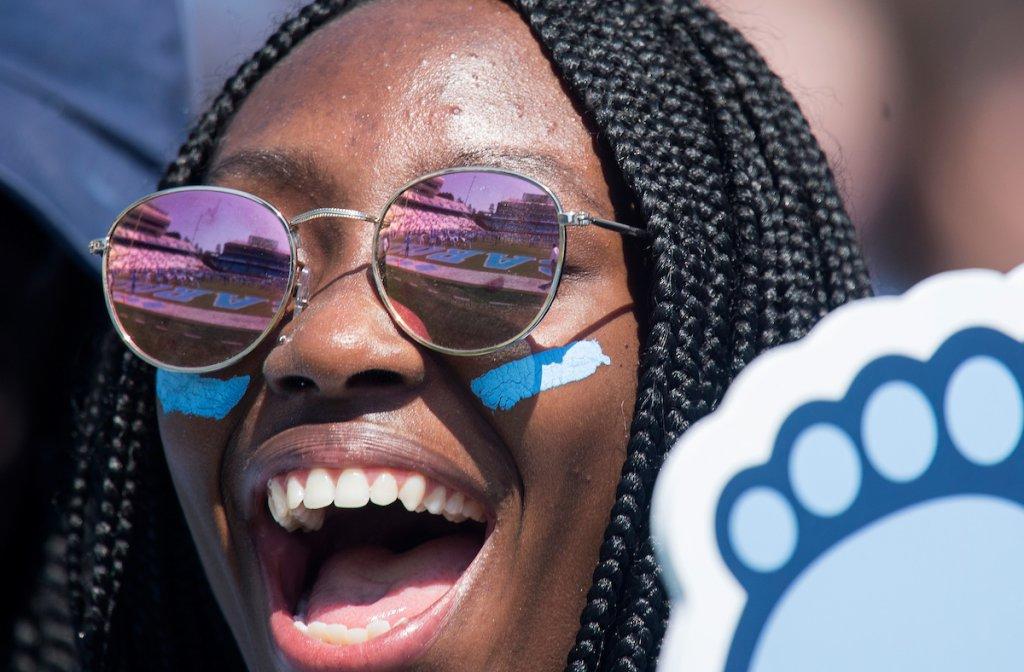 一位黑人女学生举着焦油跟形状的泡沫手指为美国欢呼.N.C. football team.