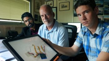 Three men look at art.