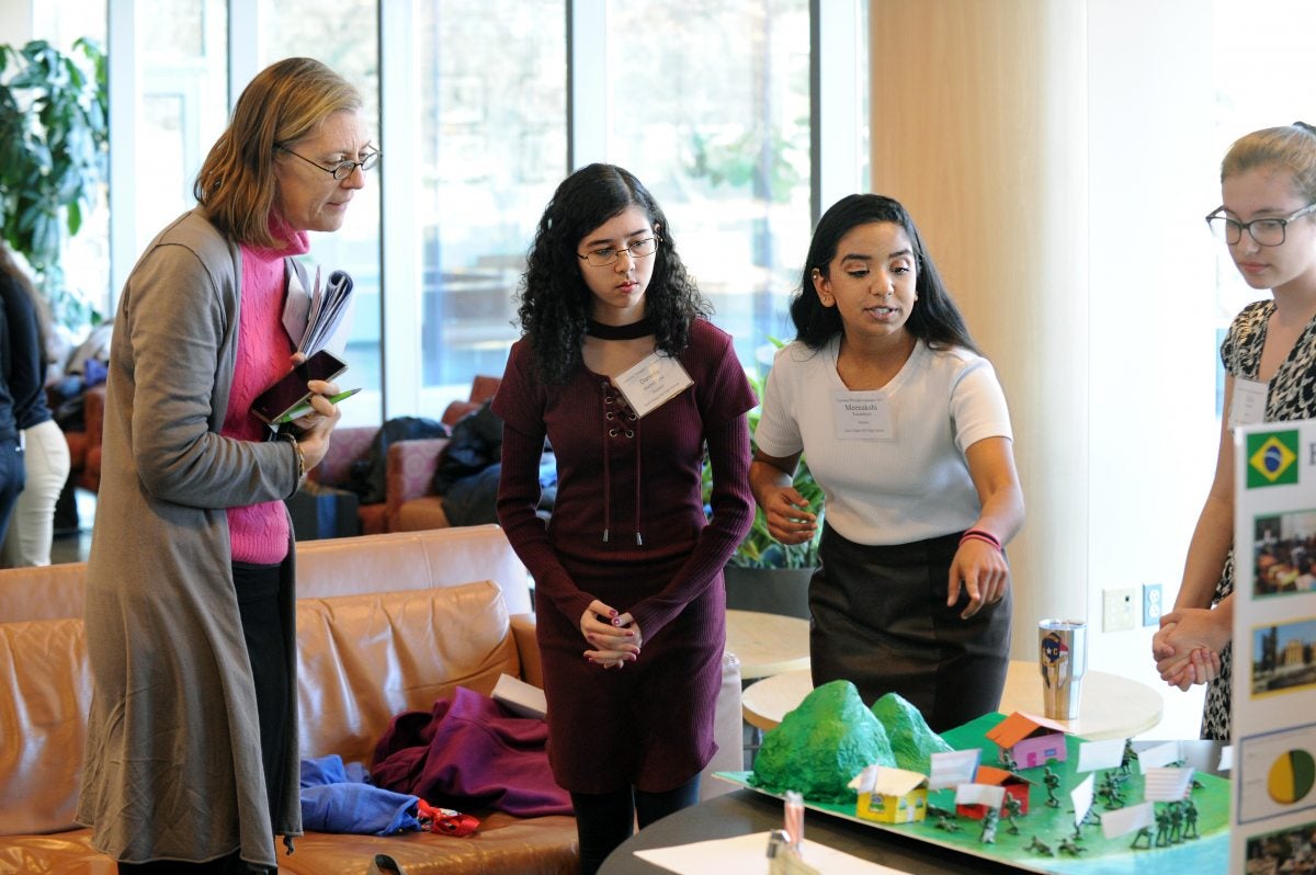 A teacher talks to students in front of a diarama.