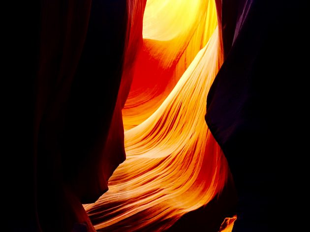 Light streaming through a black canyon lights up in yellow and orange