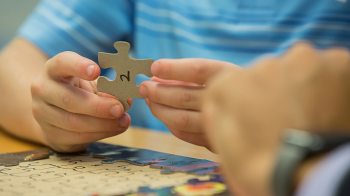 Young boy holds a puzzle piece.