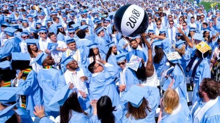 Students throw a beach ball into the air.
