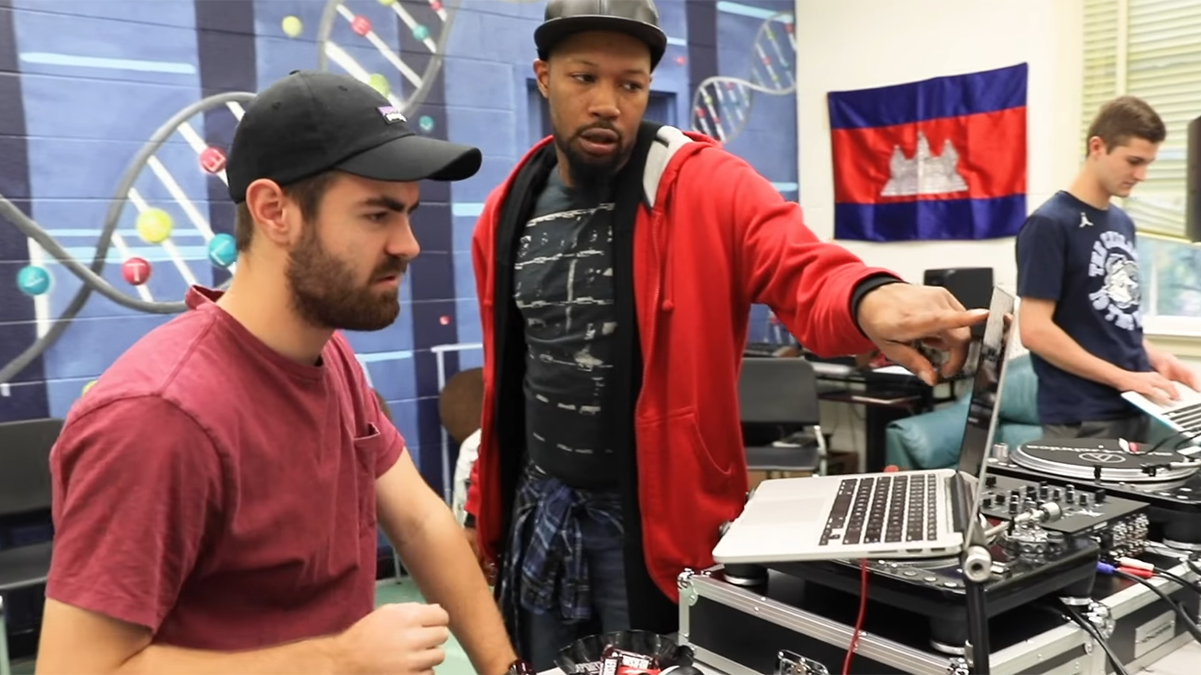 Two men look at a computer.