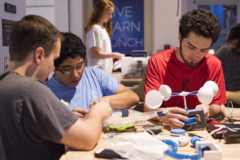 Three students work on devices at the Makeathon