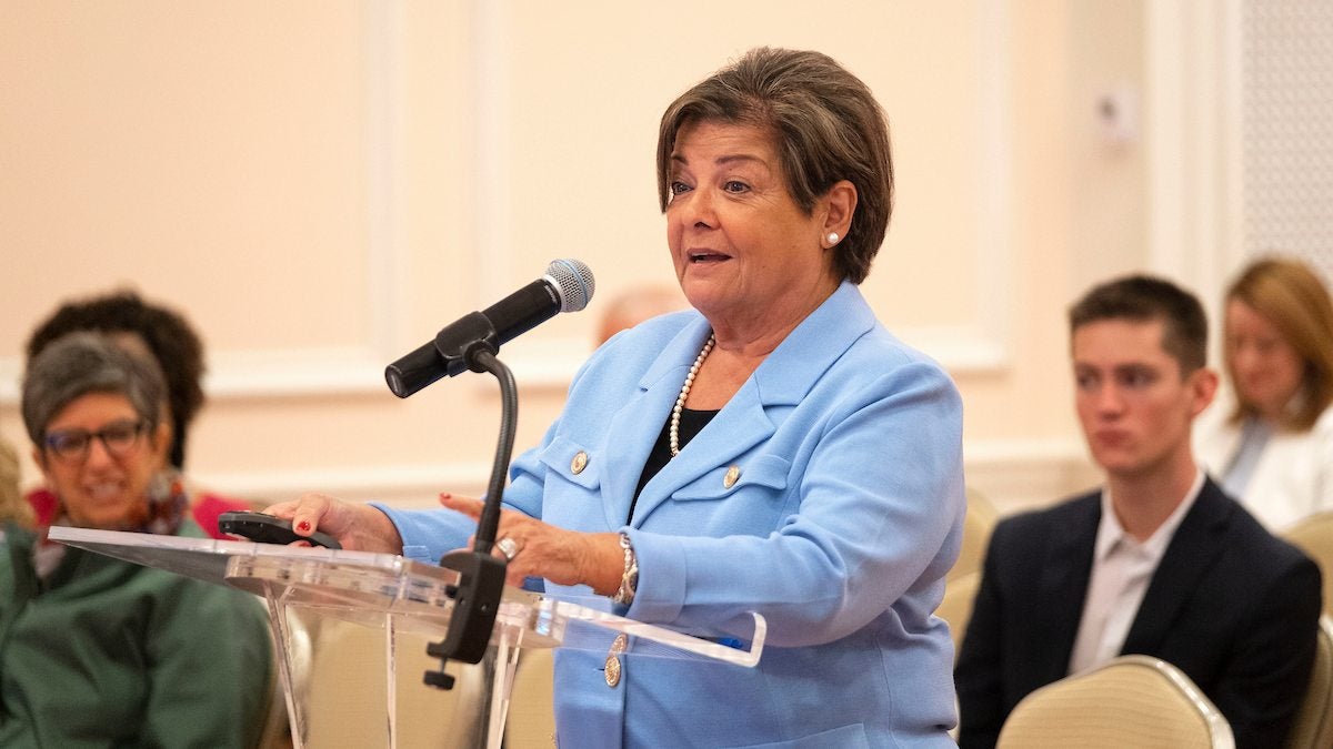 Nilda (Nena) Peragallo Montano speaks at a podium.