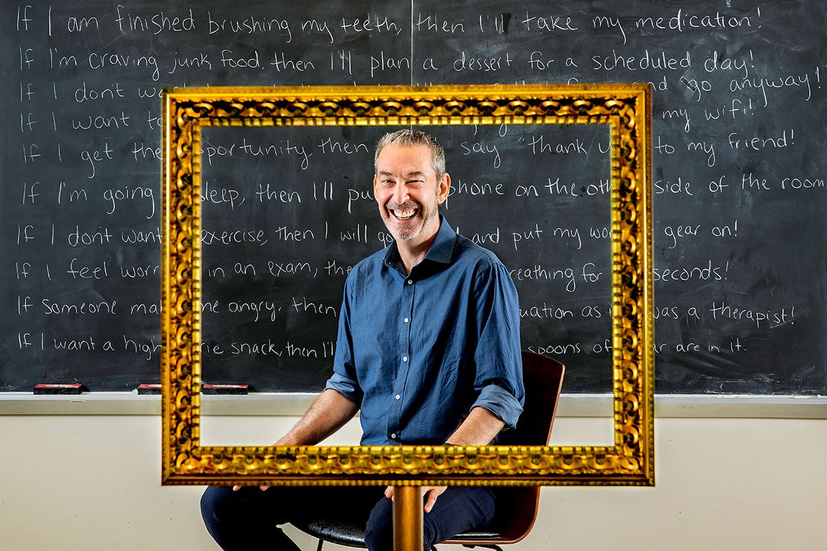 Sheeran sits in front of a chalkboard with if-then statements written all across it.