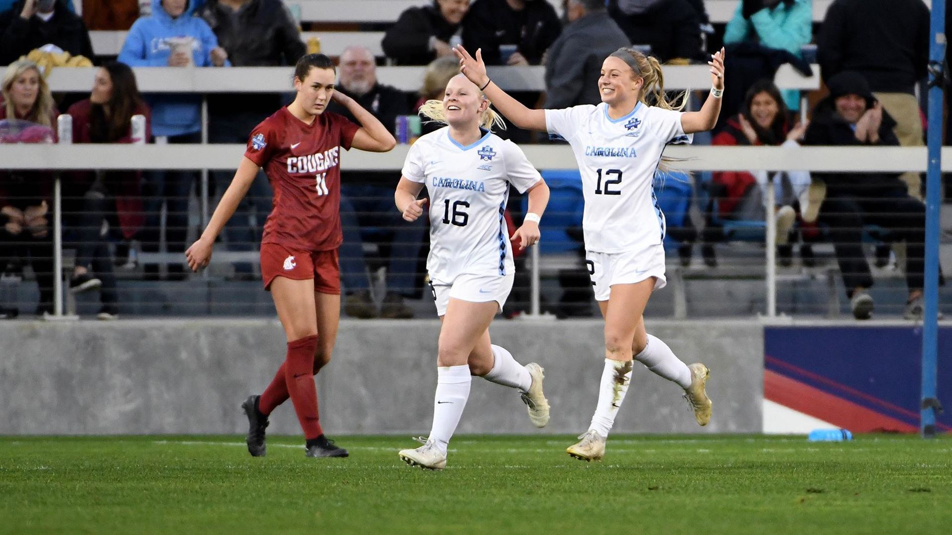The women's soccer team celebrates on the field.
