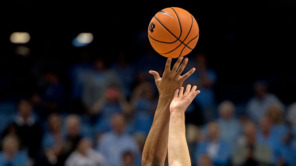 Two basketball players jump for a basketball.