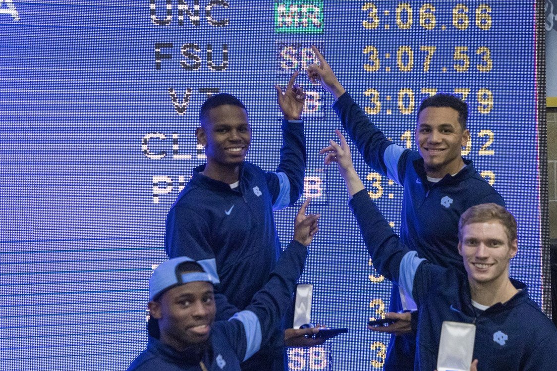 Ari Cogdell, Ryan Saint-Germain, Isaiah Palmer, Brandon Cachon stand in front of a scoreboard.