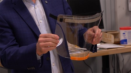 A man holds a medical face shield.