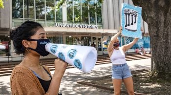 Students hold signs up for a student group.