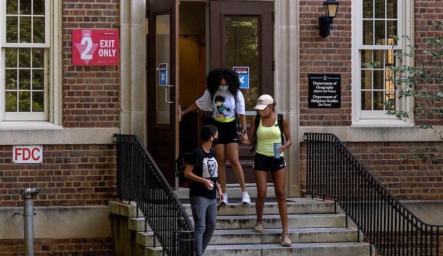 Students walk out of a campus building.
