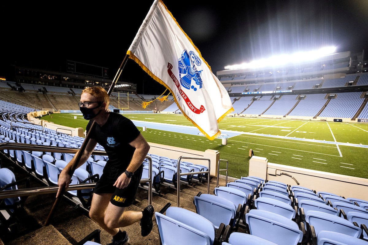 Student carries flag and runs up stadium stairs