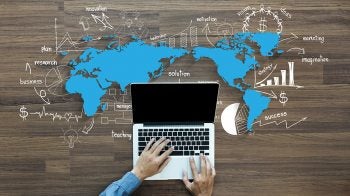 A laptop with a graphic of a world map around it.