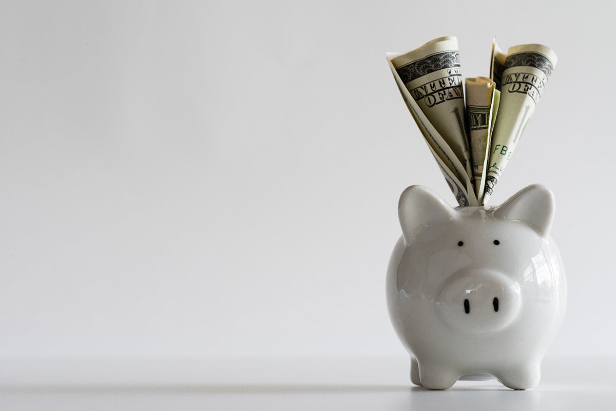 A piggy bank with money coming out of the top.