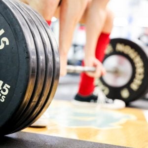 A person picks up weights in a gym.