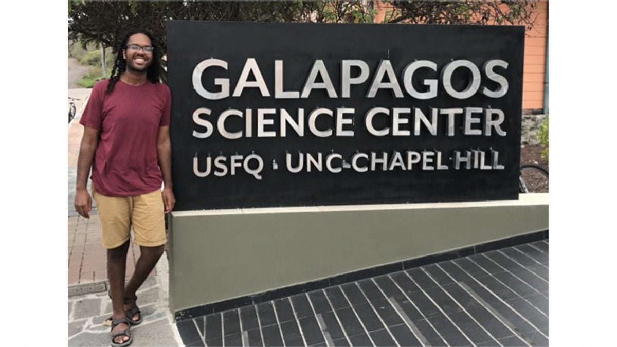 Khristopher Nicholas stands near a sign at the Galapagos Science Center.