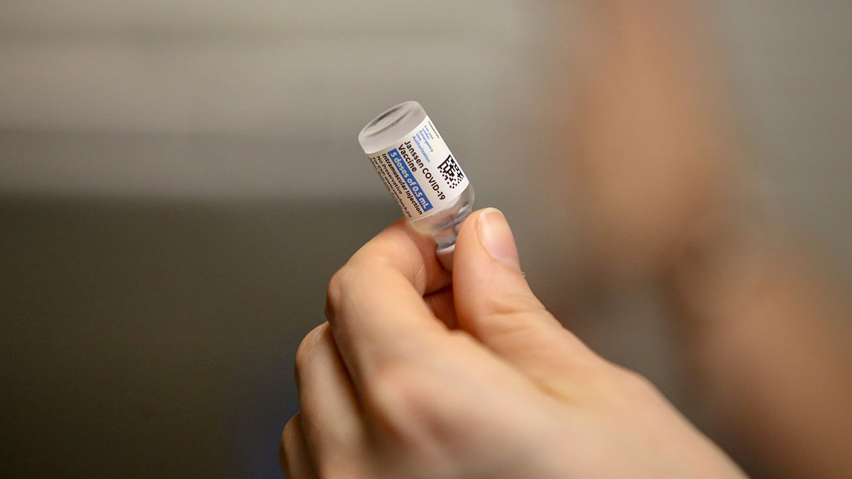 A hand holding a vile of COVID-19 vaccine.