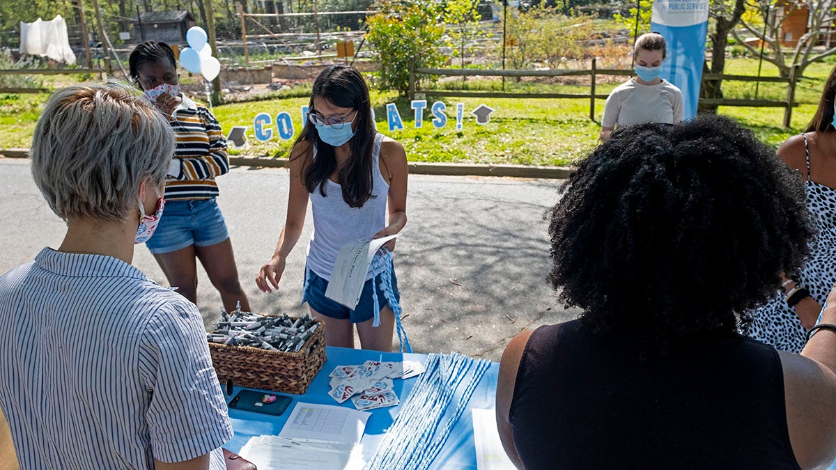 A student picks up a cooking from a table at a graduation celebration.