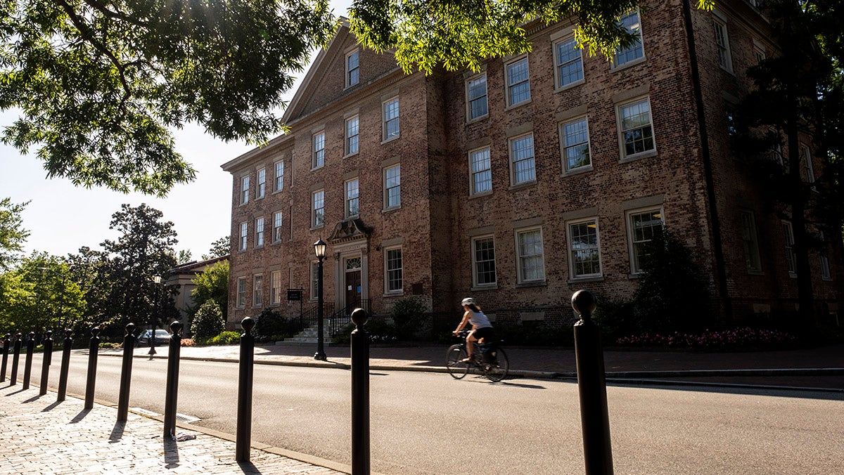 A person on a bike rides past South Building.