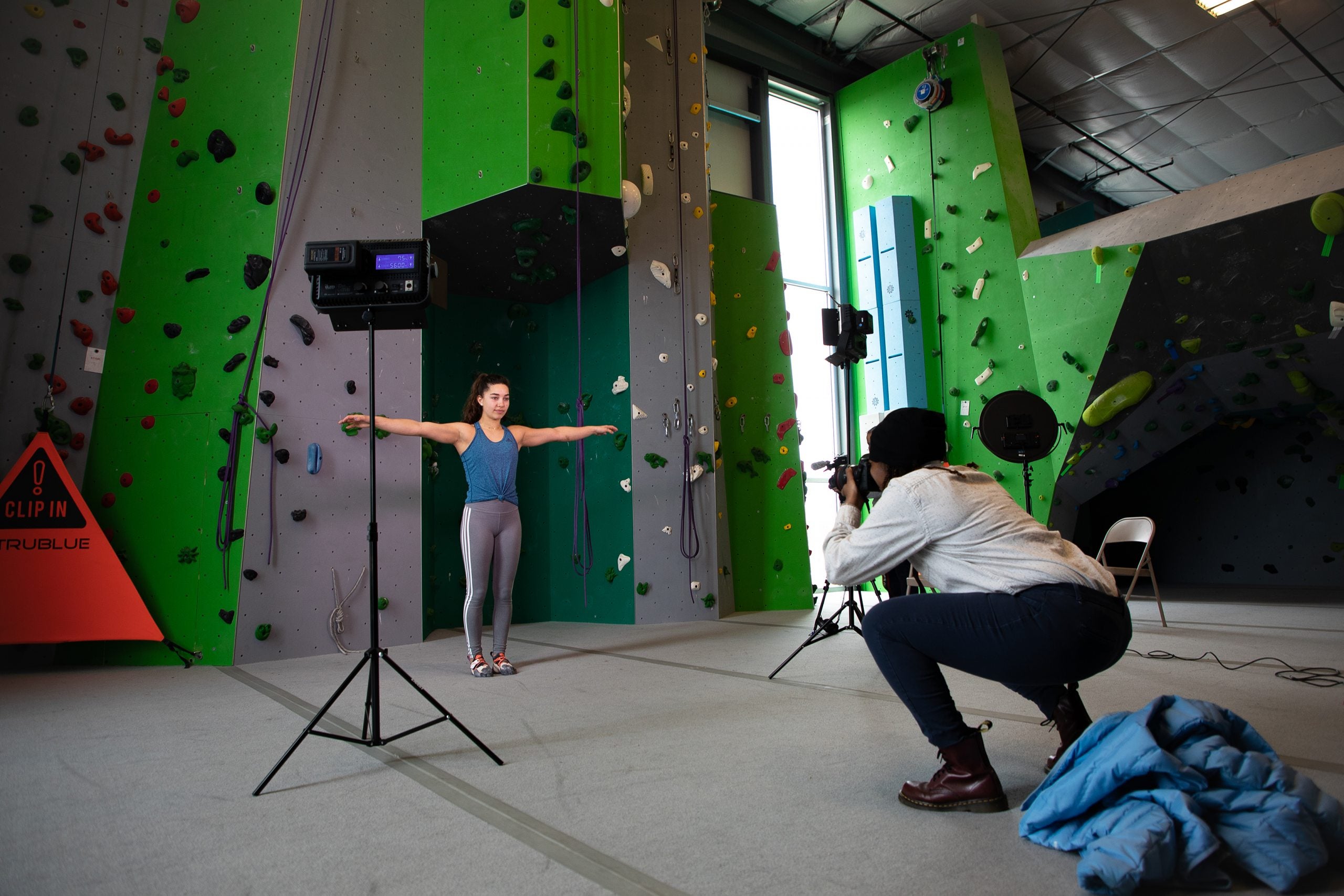 A Carolina student takes a photo of a climber in front of a rock wall.