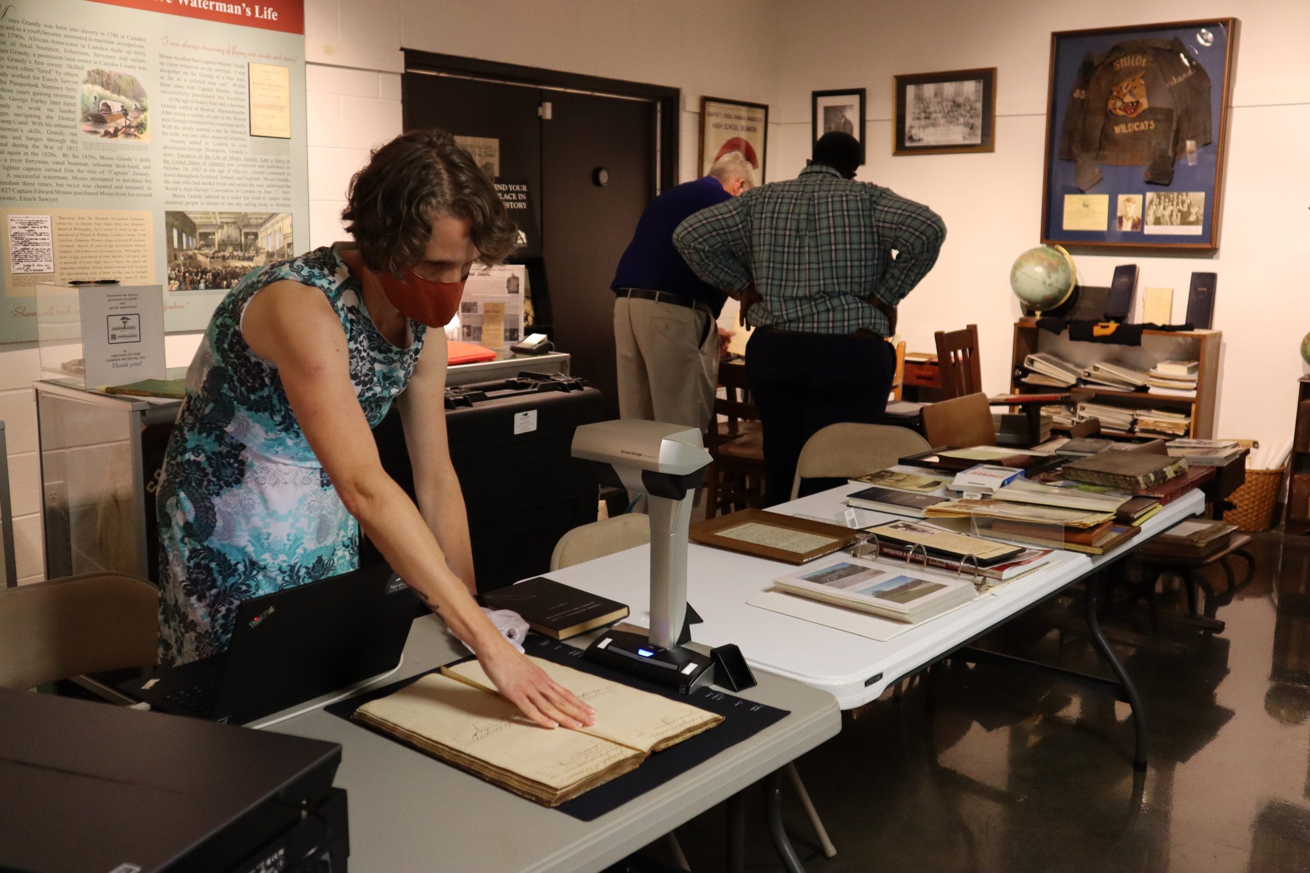 A woman uses a large scanner to scan a book.