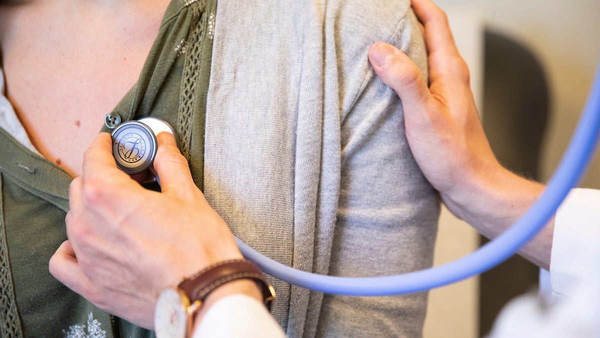 A doctor uses a stethoscope to examine a patient.