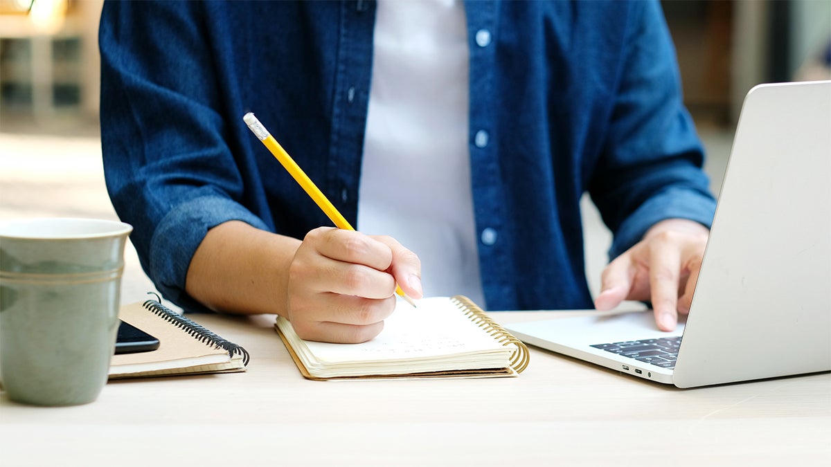A person writing on a notebook.
