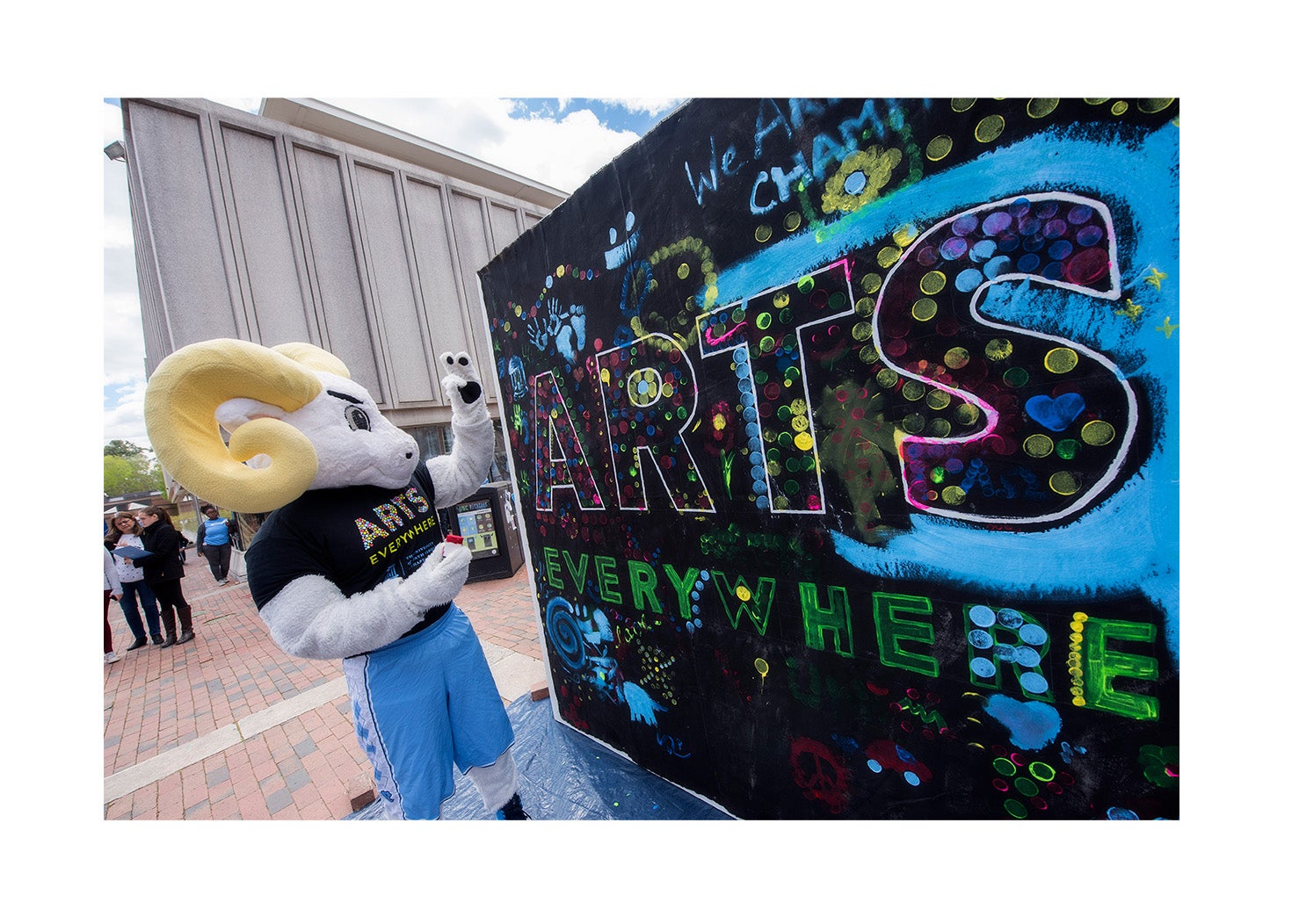 A ram mascot next to a mural painted 