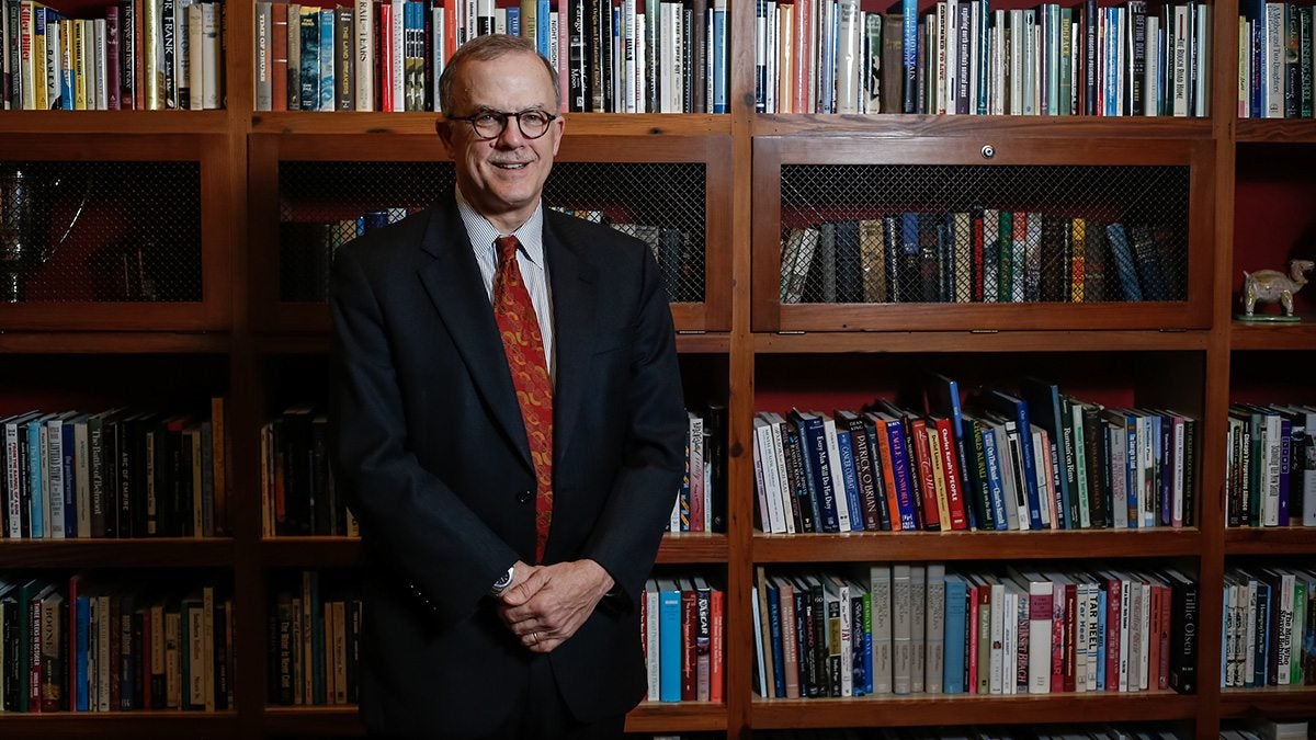 Smith Smith standing by bookshelves.