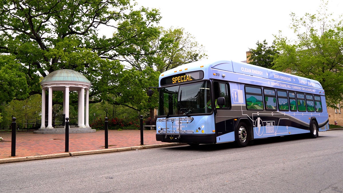 An electric bus driving past the Old Well.