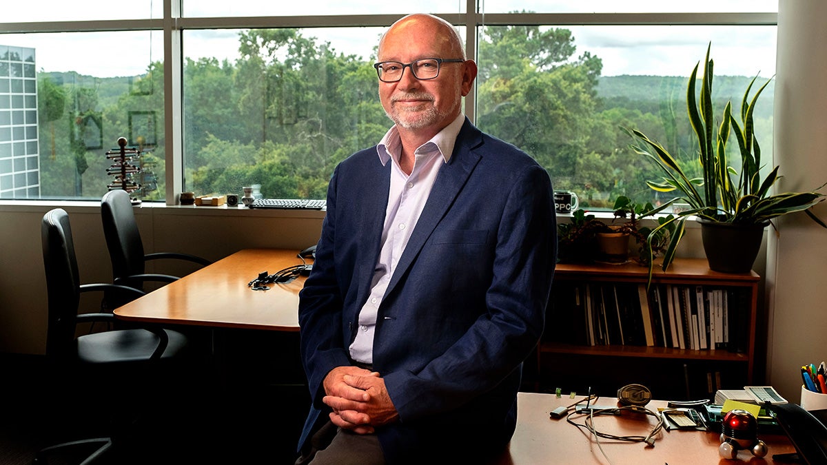 Stan Ahalt leaning against a desk in his office.