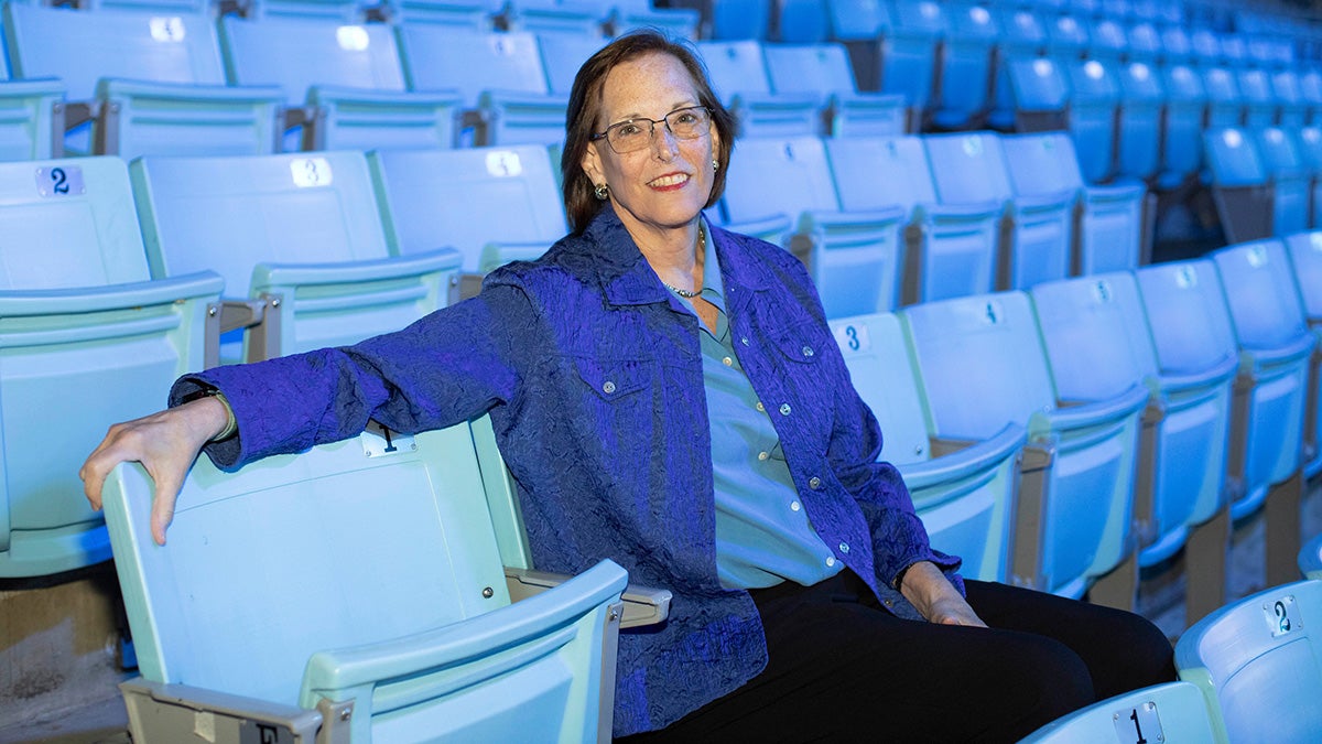 Donna Gutterman sitting Carolina blue bleachers.