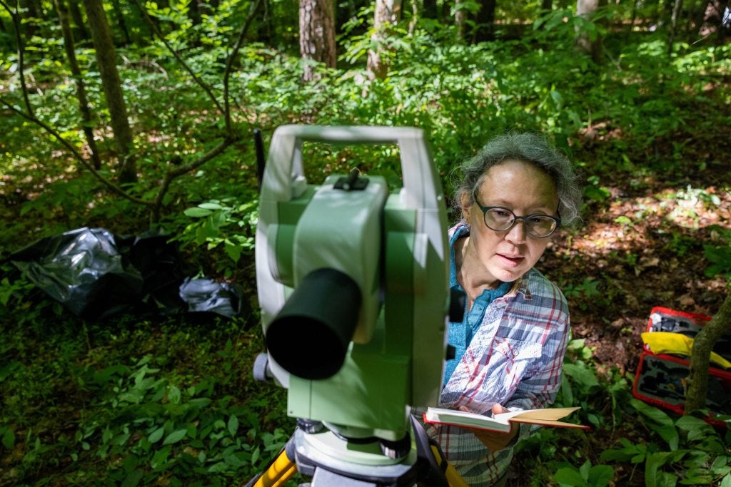 Heather Lapham peeks around a theodolite