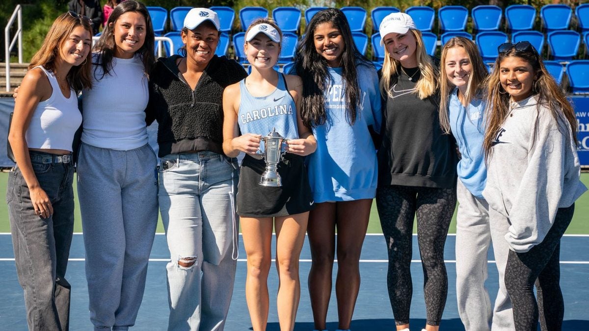 People posing for a photo in a tennis court.