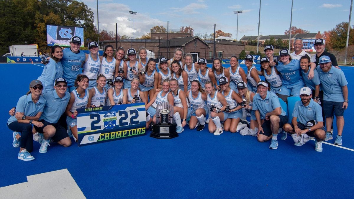 Members of the field hockey team pose behind the ACC Championship trophy and sign
