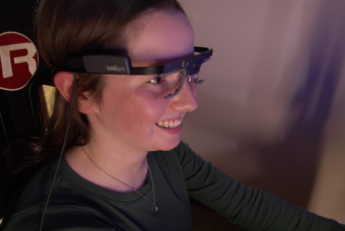 A teenager wearing glasses while in a driving simulator.