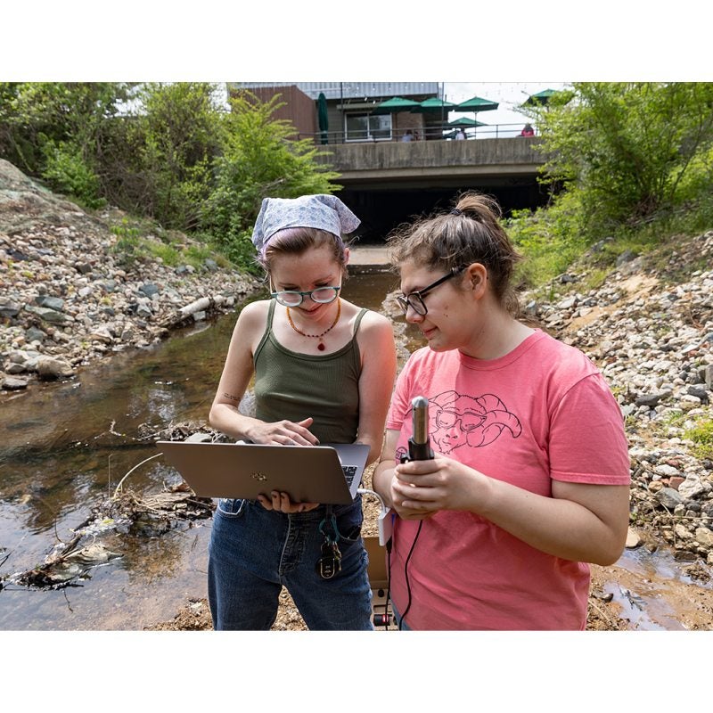 students using a senor to gauge water levels of a creek.